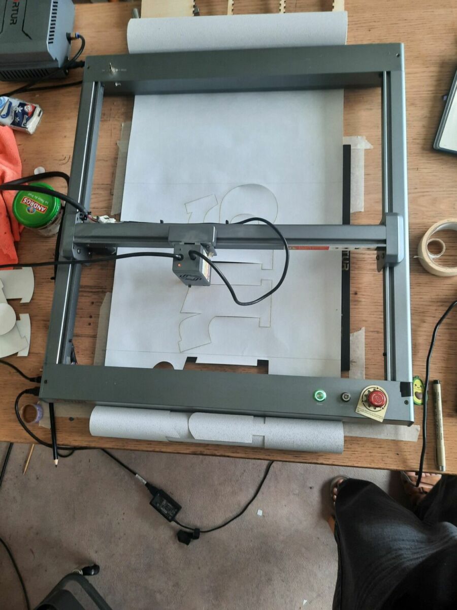 la machine de découpe en action, avec le rouleau calé de part et d'autres. On voit une ligne crayonnée qui correspond au report de section. 